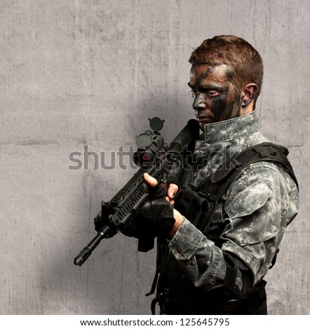 Portrait Of Soldier Holding Gun against a concrete background