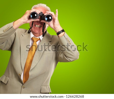 Senior Man Looking Through Binoculars On Green Background