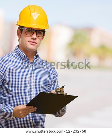Portrait Of Engineer Holding Clipboard against a street background