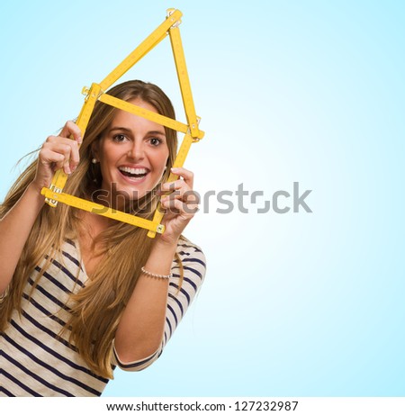 Young Woman Looking Through House Frame against a blue background
