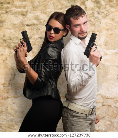 Young Couple Holding Gun against a stone wall