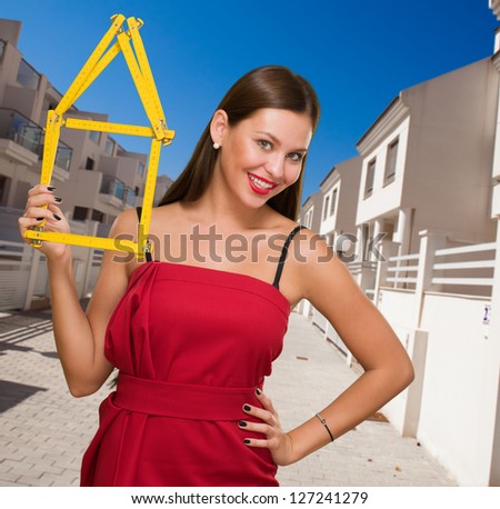Happy Young Woman Holding House Frame outside