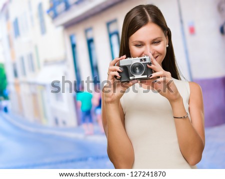 Young Woman Holding Camera against a street background