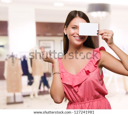 Woman holding a blank placard in front of her eye in a clothes shop