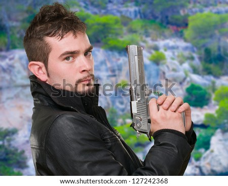 serious man holding a gun, outdoor
