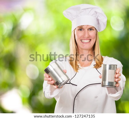 Female Chef Holding Tin against a nature background