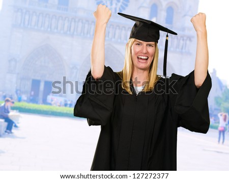 Happy Graduate Woman In Gown outside a university