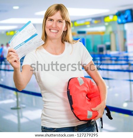 Portrait Of A Happy Woman Holding Boarding Pass And Life jacket at the airport