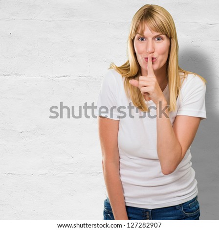 Woman With Finger On Lip against a concrete wall
