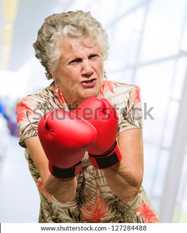 Angry Mature Woman Wearing Boxing Gloves, Indoors
