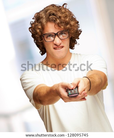 Portrait Of Young Man With Glasses Changing Channel With Tv Control, Indoor