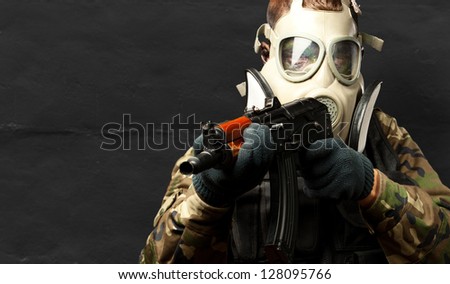 Portrait Of A Soldier With Gas Mask Aiming With Gun against a grunge background