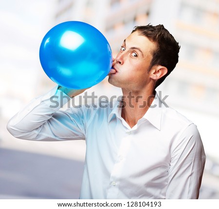 Portrait Of Young Man Blowing aÃ?Â Balloon, Outdoor