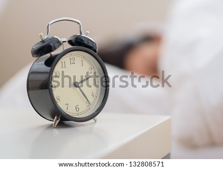 Alarm Clock In Front Of A Person Sleeping