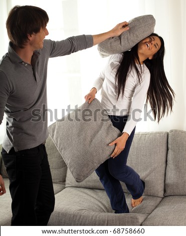 stock photo : couple fighting with pillows on the sofa