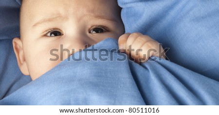 afraid baby under a blue blanket closeup