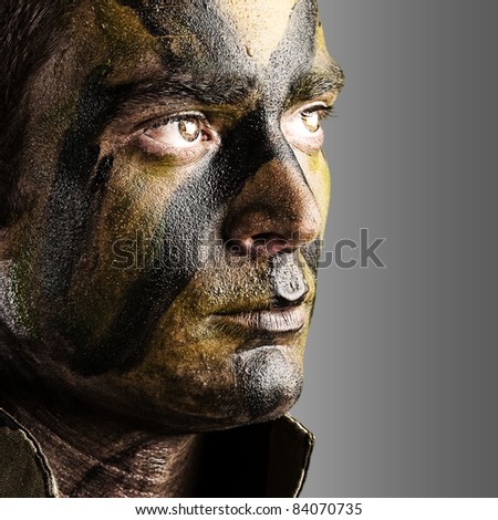 portrait of young soldier face with jungle camouflage paint against a white background