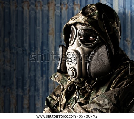 portrait of soldier with gas mask and rifle against a ship container