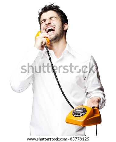 portrait of young man talking using vintage telephone laughing over white background - stock photo