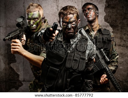 group of soldiers aiming with rifles against a grunge bricks wall