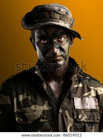 young soldier face with jungle camouflage on a yellow background