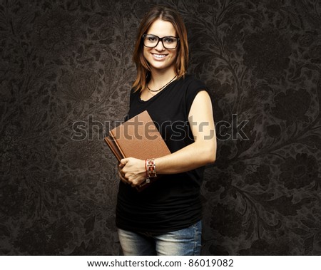 portrait of young student with glasses holding a old book against a grunge background
