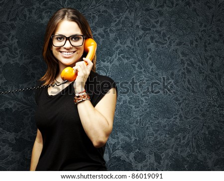 portrait of young woman talking using a vintage telephone against a vintage background