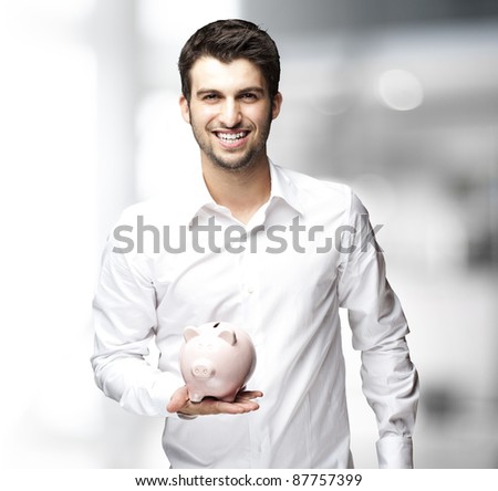 Portrait of young man holding a piggy bank indoor