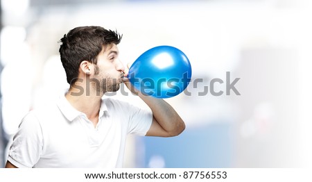 portrait of young man blowing a balloon indoor