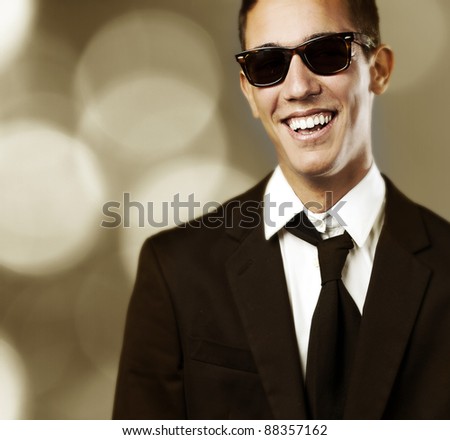 portrait of a serious business man doing approve gesture against a golden lights background