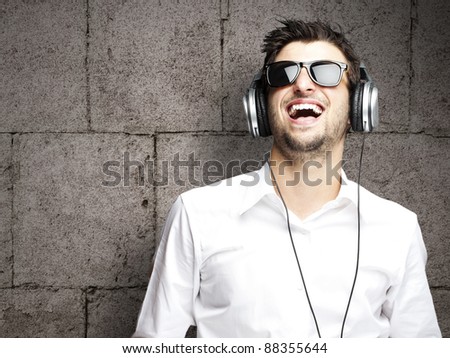 portrait of a handsome young man listening to music against a grunge bricks wall
