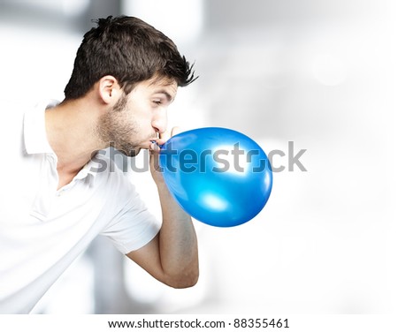 portrait of young man blowing a balloon indoor