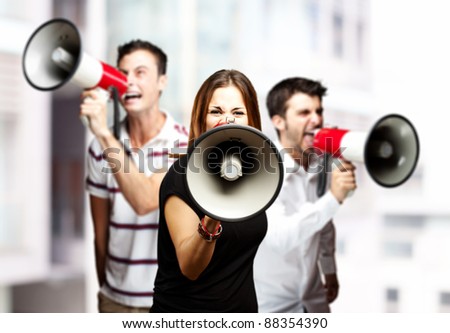 portrait of a angry  group of employees shouting using megaphones against a city background