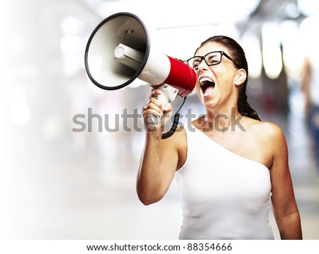 portrait of middle aged woman shouting with megaphone in a crowded place