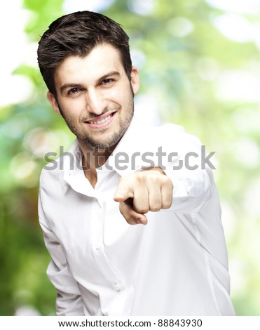 portrait of young man smiling and pointing with finger against a nature background
