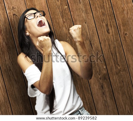 portrait of young woman doing good symbol against a wooden wall woman win gesture against a wooden wall