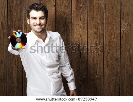 portrait of young man holding cd against a wooden wall