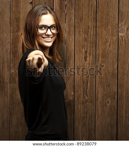 portrait of young woman pointing with finger against a wooden wall