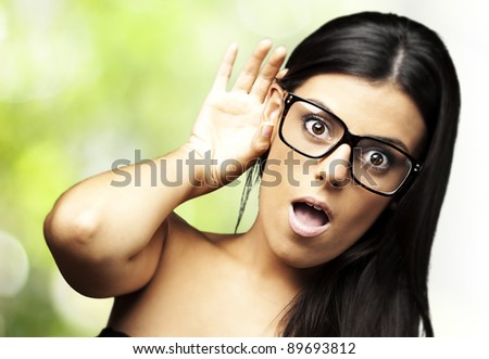 portrait of young woman surprised hearing a sound against nature background