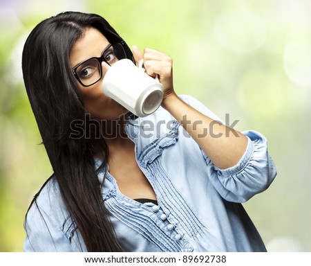 portrait of young woman drinking coffee against a nature background