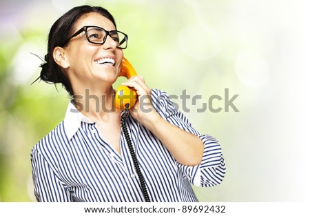 portrait of a middle aged woman talking on vintage telephone against a nature background