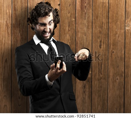 portrait of business man angry with technology against a wooden wall