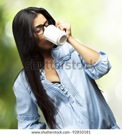 portrait of a pretty young woman drinking coffee on a cup against a nature background