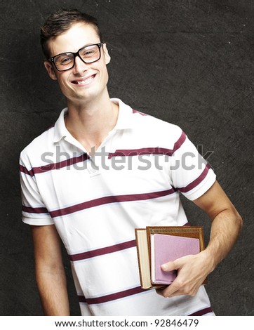 portrait of young student with glasses holding a book against a grunge background