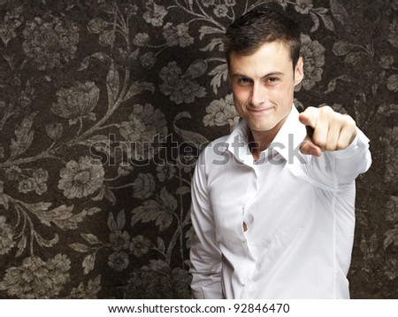 portrait of young man pointing with finger against a vintage wall