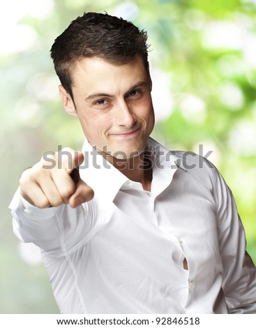 portrait of young man pointing with finger against a nature background