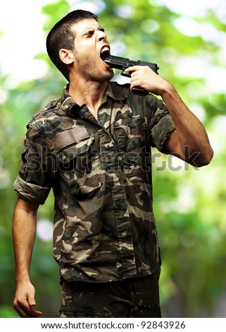 young soldier wearing a jungle camouflage committing suicide against a jungle background