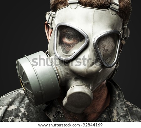 portrait of young soldier wearing gas mask against a black background