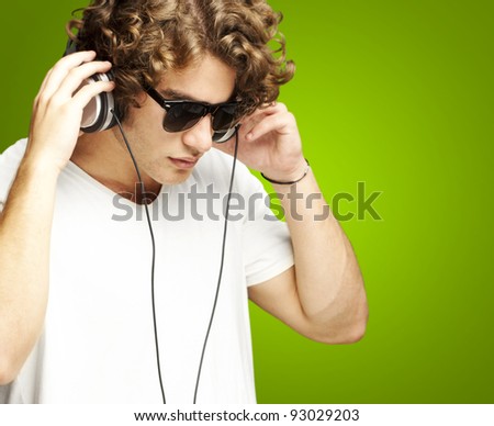 portrait of a handsome young man listening music against a green background