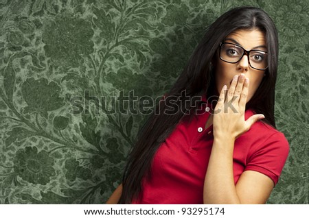 portrait of a young woman covering her mouth with hand against a vintage wall